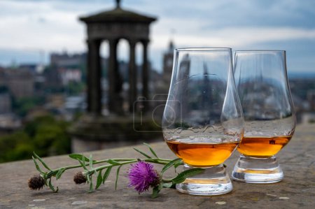 Foto de Dos vasos de whisky escocés de malta simple y vista desde Calton Hill hasta el parque y las partes antiguas de la ciudad de Edimburgo en el lluvioso día de verano, Escocia, Reino Unido - Imagen libre de derechos