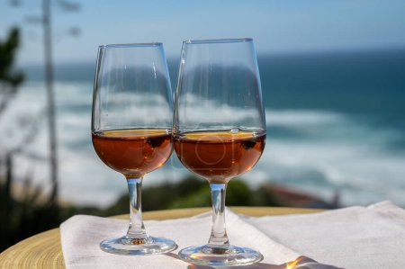 Degustación de moscatel de setubal dulce o vino portugués de porto y vista sobre el soleado océano Atlántico azul cerca de Sintra en la zona de Lisboa, Portugal