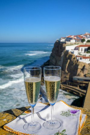 Téléchargez les photos : Verres de champagne mousseux vin blanc et vue sur les maisons blanches du village pittoresque Azenhas do mar, Lisbonne, Portugal - en image libre de droit