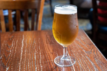 Téléchargez les photos : Pint glass of british light pilsner ot lager beer served in old vintage English pub, close up - en image libre de droit