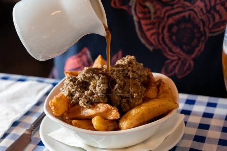 Scottish traditional snack food, hand cut potato chips topped with haggis and gravy served in old tavern, Edinburgh, Scotland