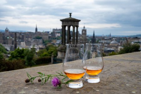 Foto de Dos vasos de whisky escocés de malta simple y vista desde Calton Hill hasta el parque y las partes antiguas de la ciudad de Edimburgo en el lluvioso día de verano, Escocia, Reino Unido - Imagen libre de derechos