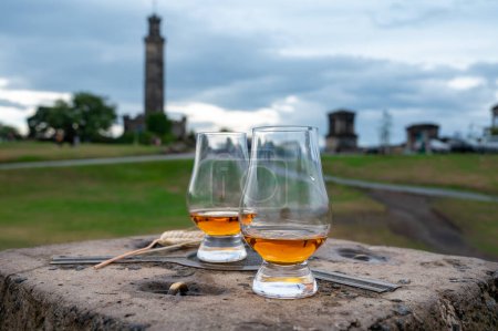 Foto de Tasting of single malt scotch whisky in glasses with panoramic view from Calton hill to new and old parts of Edinburgh city in rainy summer day, Scotland, UK - Imagen libre de derechos