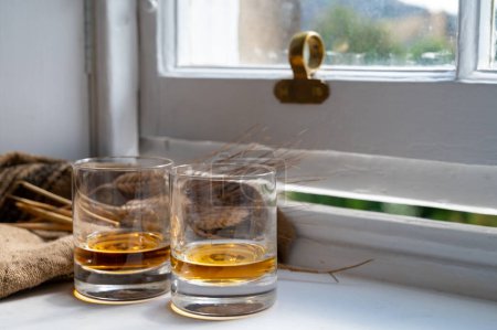 Foto de Two glasses of single malt scotch whisky served on old white wooden window sill in Scottisch house in Edinburgh, Scotland, UK - Imagen libre de derechos