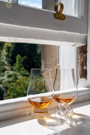 Foto de Two glasses of single malt scotch whisky served on old window sill in Scottisch house with view on old part of Edinburgh, Scotland, UK, dram of whiskey - Imagen libre de derechos