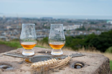 Foto de Tasting of single malt scotch whisky in glasses with panoramic view from Calton hill to new and old parts of Edinburgh city in rainy summer day, Scotland, UK - Imagen libre de derechos