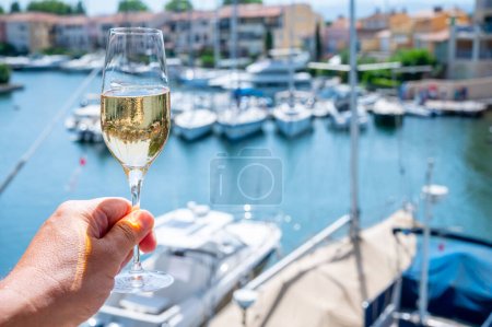Fête du Nouvel An, dégustation de champagne brut français mousseux dans des verres dans le port de plaisance de Port Grimaud près de Saint-Tropez, vacances sur la Côte d'Azur, France