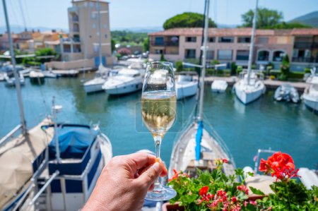 Téléchargez les photos : Fête du Nouvel An, dégustation de champagne brut français mousseux dans des verres dans le port de plaisance de Port Grimaud près de Saint-Tropez, vacances sur la Côte d'Azur, France - en image libre de droit