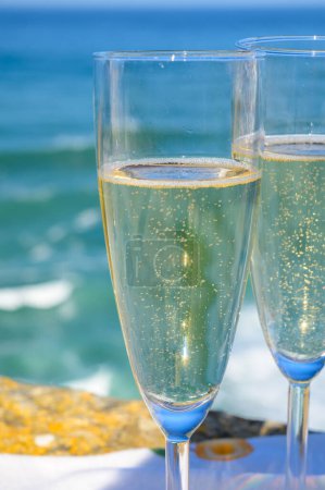 Téléchargez les photos : Lunettes de champagne mousseux et vue ensoleillée sur l'océan Atlantique bleu, région de Lisbonne, Portugal - en image libre de droit