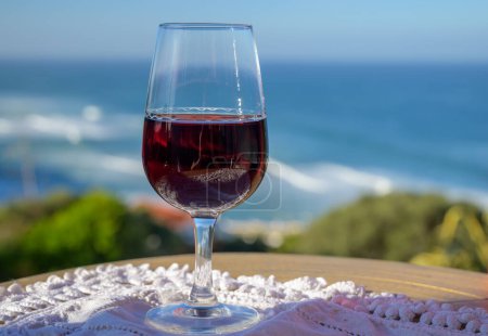 Photo for Tasting of tawny porto wine and   view on sandy beach and blue Atlantic ocean near Sintra in Lisbon area, wine of Portugal - Royalty Free Image