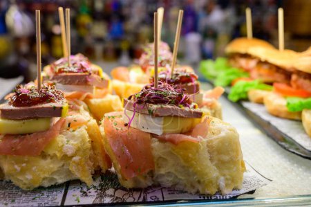 Weißes Brett mit typischen baskischen Snacks, Pinchos oder Pinxtos Spieße mit kleinen Brotstücken, Zucchini, Meeresfrüchten, Eiern, Käse, serviert in einer Bar in San-Sebastian oder Bilbao, Spanien