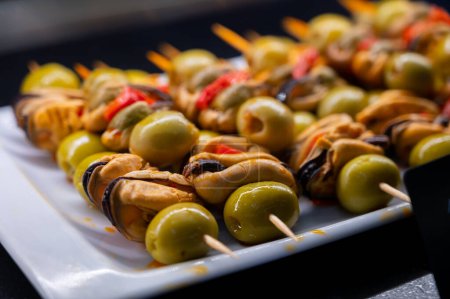 Typical snack of Basque Country, pinchos or pinxtos skewers with small pieces of bread, sea food, eggs, cheese, jamon served in bar in San-Sebastian or Bilbao, Spain, close up