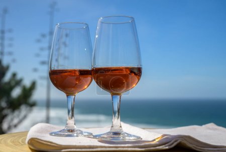 Degustación de moscatel de setubal dulce o vino portugués de porto y vista sobre el soleado océano Atlántico azul cerca de Sintra en la zona de Lisboa, Portugal
