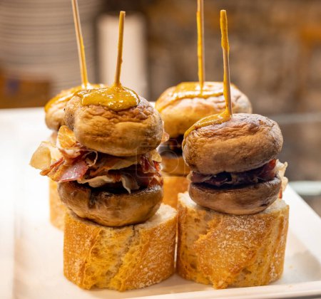 Snack típico del País Vasco, pinchos o pinchos pinchos con pequeños trozos de pan, champiñones y quesos servidos en un bar de San Sebastián o Bilbao, España