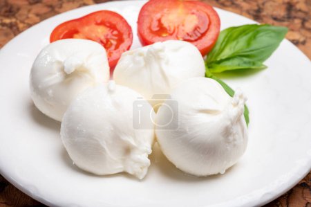 Photo for Eating of fresh handmade soft Italian cheese from Puglia, white balls of burrata or burratina cheese made from mozzarella and cream filling close up - Royalty Free Image