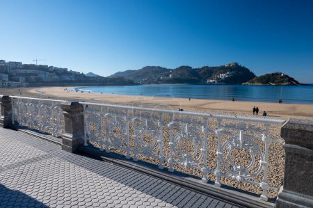 Téléchargez les photos : Walking on promenade along white sandy La Concha beach in central part of Donostia or San Sebastian city, Basque Country, Spain in sunny day - en image libre de droit