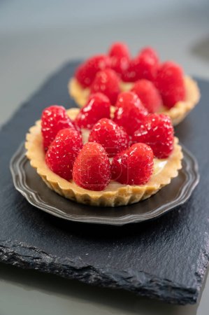 Photo for Artisanal baked small tart with cream and fresh ripe red raspberry, tasty french dessert - Royalty Free Image