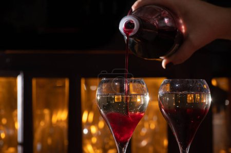Téléchargez les photos : Boire du Kir Royal, cocktail français à l'apéritif à base de crème de cassis garni de champagne, typiquement servi dans des verres à tulipes servis dans un bar - en image libre de droit