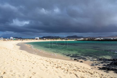 Weißer Sand, blaues Wasser und stürmische Wolken am Strand von La Concha, Surferdorf El Cotillo, Fuerteventura, Kanarische Inseln, Spanien