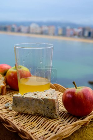 Essen und Trinken in Asturien, blauer Kuhcabrales-Käse aus Arenas, serviert im Freien mit einem Glas natürlichem Apfelmost und Blick auf den Strand San Lorenzo in Gijon, Spanien