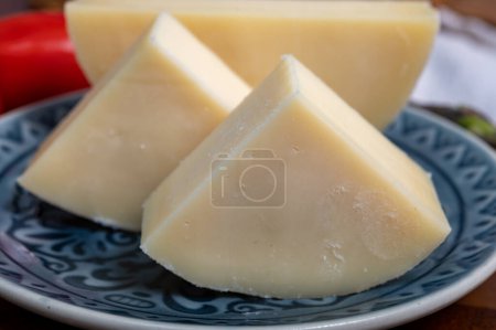 Téléchargez les photos : Fromage italien, fromage de vache Provolone dolce de Crémone servi avec du pain d'olive et des tomates close up. - en image libre de droit
