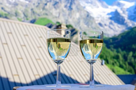 Téléchargez les photos : Boire du vin blanc sec Roussette de Savoie et Vin de Savoie Vin français de Savoie avec vue sur les Hautes Alpes avec neige au sommet en été. - en image libre de droit