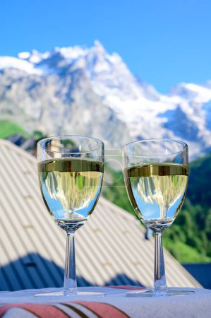 Téléchargez les photos : Boire du vin blanc sec Roussette de Savoie et Vin de Savoie Vin français de Savoie avec vue sur les Hautes Alpes avec neige au sommet en été. - en image libre de droit