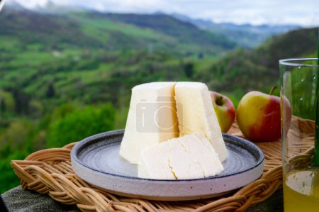 Téléchargez les photos : Afuega'l pitu espagnol fromage de vache non pasteurisé des Asturies servi en plein air avec des pommes et vue sur les pentes verdoyantes des montagnes Picos de Europa, Espagne - en image libre de droit