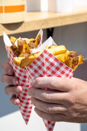 Téléchargez les photos : Traditional street food in Belgium and Netherlands, French fried potatoes chips with mayonnaise sauce in paper cone bag. - en image libre de droit