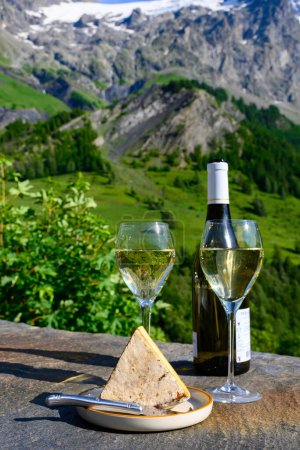 Téléchargez les photos : Fromage et vin, verres de vin blanc sec Roussette de Savoie et Vin de Savoie de Savoie avec tomme et vue sur les Hautes Alpes avec neige au sommet - en image libre de droit