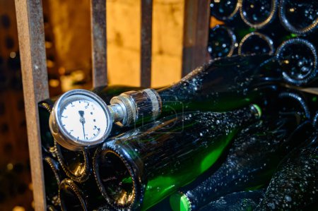 Foto de Caminar en profundas cuevas subterráneas con botellas en bastidores de madera, elaboración tradicional de vino espumoso de champán de chardonnay y pinor noir uvas en Epernay, Champagne, Francia - Imagen libre de derechos
