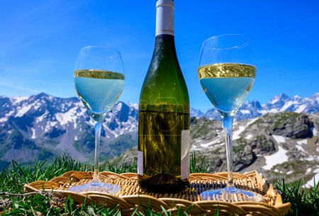 Téléchargez les photos : Verre et bouteille de vin blanc sec Roussette de Savoie ou Vin de Savoie de la région de Savoie servi sur la frontière du Col du Galibier Région de Savoie, France, vue sur les Alpes. - en image libre de droit