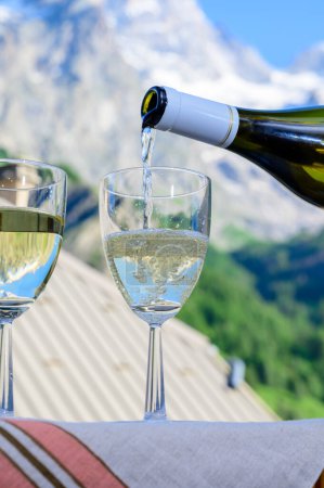 Foto de Bebida de blanco seco Roussette de Savoie y Vin de Savoie vino francés de la región de Saboya con vista a las montañas de los Altos Alpes con nieve en la parte superior - Imagen libre de derechos