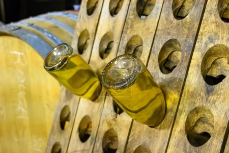 Foto de Visita de cuevas subterráneas con barriles, tanques, botellas en bastidores de madera, elaboración tradicional de vino espumoso de champán en Cote des Bar, al sur de Champagne, Francia - Imagen libre de derechos