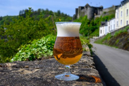 Copa de cerveza fuerte abadía belga rubia en la pared del castillo viejo en el día de verano soleado con buenas vistas del casco antiguo Bouillon, Bélgica