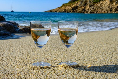 Téléchargez les photos : Heure d'été en Provence, deux verres de vin de rose froid sur une plage de sable fin près de Saint-Tropez par temps ensoleillé, département du Var, France. - en image libre de droit
