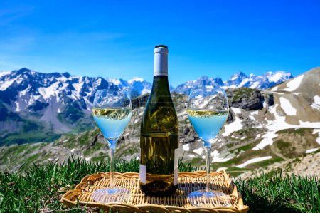Téléchargez les photos : Verre et bouteille de vin blanc sec Roussette de Savoie ou Vin de Savoie de la région de Savoie servi sur la frontière du Col du Galibier Région de Savoie, France, vue sur les Alpes. - en image libre de droit