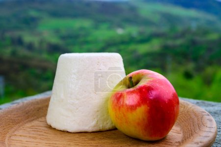 Téléchargez les photos : Afuega'l pitu espagnol fromage de vache non pasteurisé des Asturies servi en plein air avec des pommes et vue sur les pentes verdoyantes des montagnes Picos de Europa, Espagne - en image libre de droit