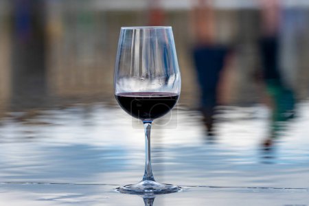 Photo for Tasting of Bordeaux blended red wine and view on city Bordeaux on background, left bank of Gironde Estuary, France. Glass of red French wine. - Royalty Free Image