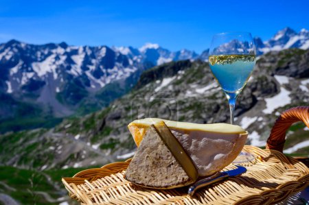 Foto de Colección de quesos, queso Reblochon y Tomme de Savoie de la región de Savoy en los Alpes franceses, queso de leche de vaca suave servido al aire libre, vista de las cumbres nevadas de los Alpes franceses - Imagen libre de derechos