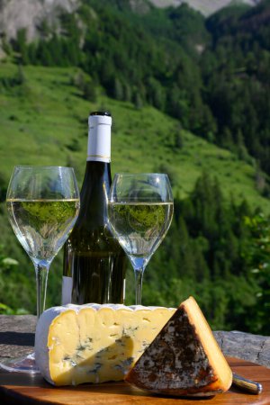 Téléchargez les photos : Fromage et vin, verres de vin blanc sec Roussette de Savoie et Vin de Savoie de Savoie avec tomme et vue sur les Hautes Alpes avec neige au sommet - en image libre de droit