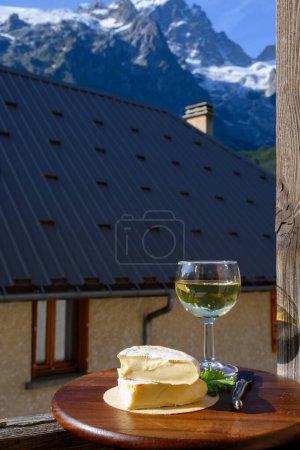 Téléchargez les photos : Reblochon Fromage français fabriqué en Haute-Savoie, Roussette de Savoie blanche ou Vin de Savoie avec vue sur le vieux village d'alripne et les sommets des Hautes Alpes - en image libre de droit