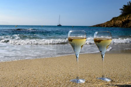 Téléchargez les photos : Heure d'été en Provence, deux verres de champagne froid crémant mousseux sur une plage de sable fin près de Saint-Tropez par temps ensoleillé, département du Var, vacances en France - en image libre de droit