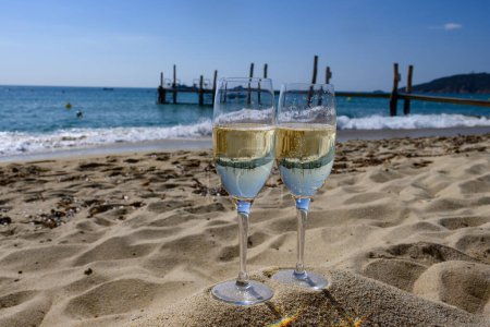 Photo for Summer time in Provence, two glasses of cold champagne cremant sparkling wine on famous Pampelonne sandy beach near Saint-Tropez in sunny day, Var department, vanation in France - Royalty Free Image