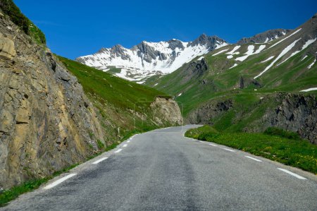 Narrow mountains road from Col de Lautaret to Col du Calibier, Mountains and green alpine meadows views of Massif des Ecrins, Hautes Alpes, France in summer
