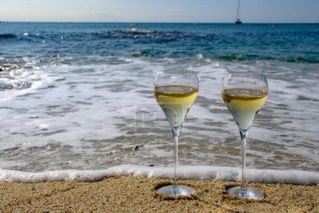 Téléchargez les photos : Heure d'été en Provence, deux verres de champagne froid crémant mousseux sur une plage de sable fin près de Saint-Tropez par temps ensoleillé, département du Var, vacances en France - en image libre de droit