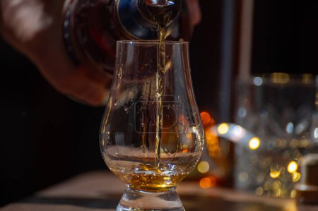 Foto de Verter whisky, vasos de malta simple y whisky escocés mezclado servido en un bar en Edimburgo, Escocia, Reino Unido con luces de fiesta en el fondo. - Imagen libre de derechos