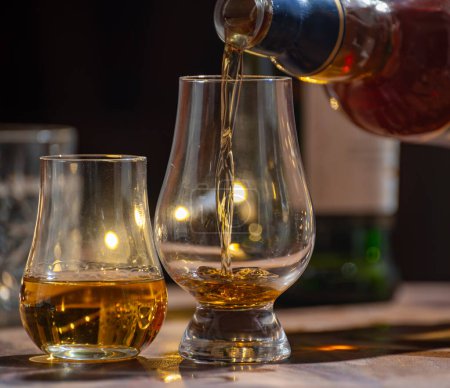 Foto de Verter whisky, vasos de malta simple y whisky escocés mezclado servido en un bar en Edimburgo, Escocia, Reino Unido con luces de fiesta en el fondo. - Imagen libre de derechos