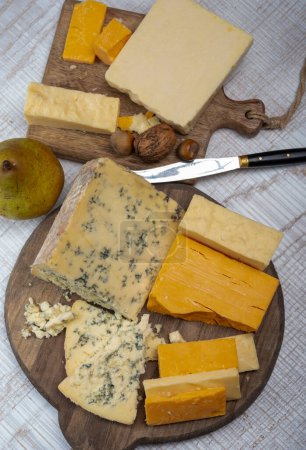 Téléchargez les photos : Collection de fromages anglais, fromage cheddar mûr et coloré et fromage bleu stilton semi-mou et friable dans une assiette - en image libre de droit