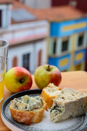 Foto de Maridaje de comida en Asturias, queso cabrales de vaca azul de cuevas en Arenas servido al aire libre con vaso de sidra de manzana natural y vista sobre la playa de San Lorenzo en Gijón, España - Imagen libre de derechos